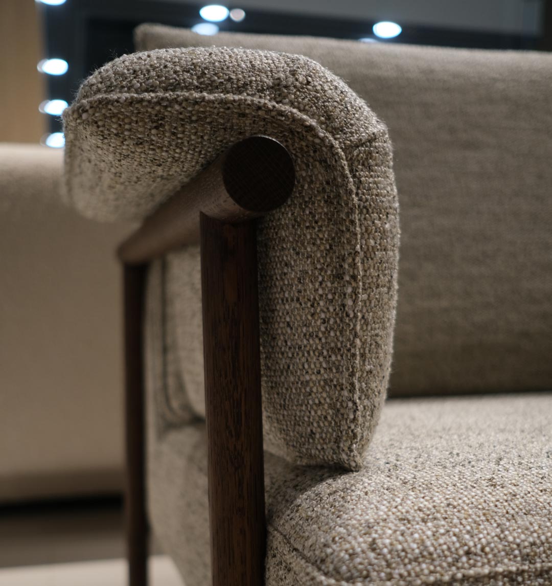 01 Detail ujęcie podłokietnika fotela Bizzarto w showroomie Bizzarto Poznań — tkanina boucle w beżowym odcieniu, drewniana rama, meble tapicerowane premium.